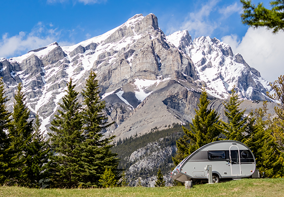 Kleiner Wohnwagen auf Naturwiese vor Alpen 2026