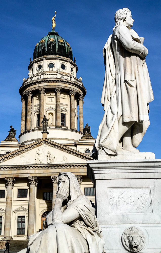 Schillerdenkmal mit einer allegorischen Frauenfigur zur "Philosophie" auf dem Gendarmenmarkt. Im Hintergrund der Französische Dom