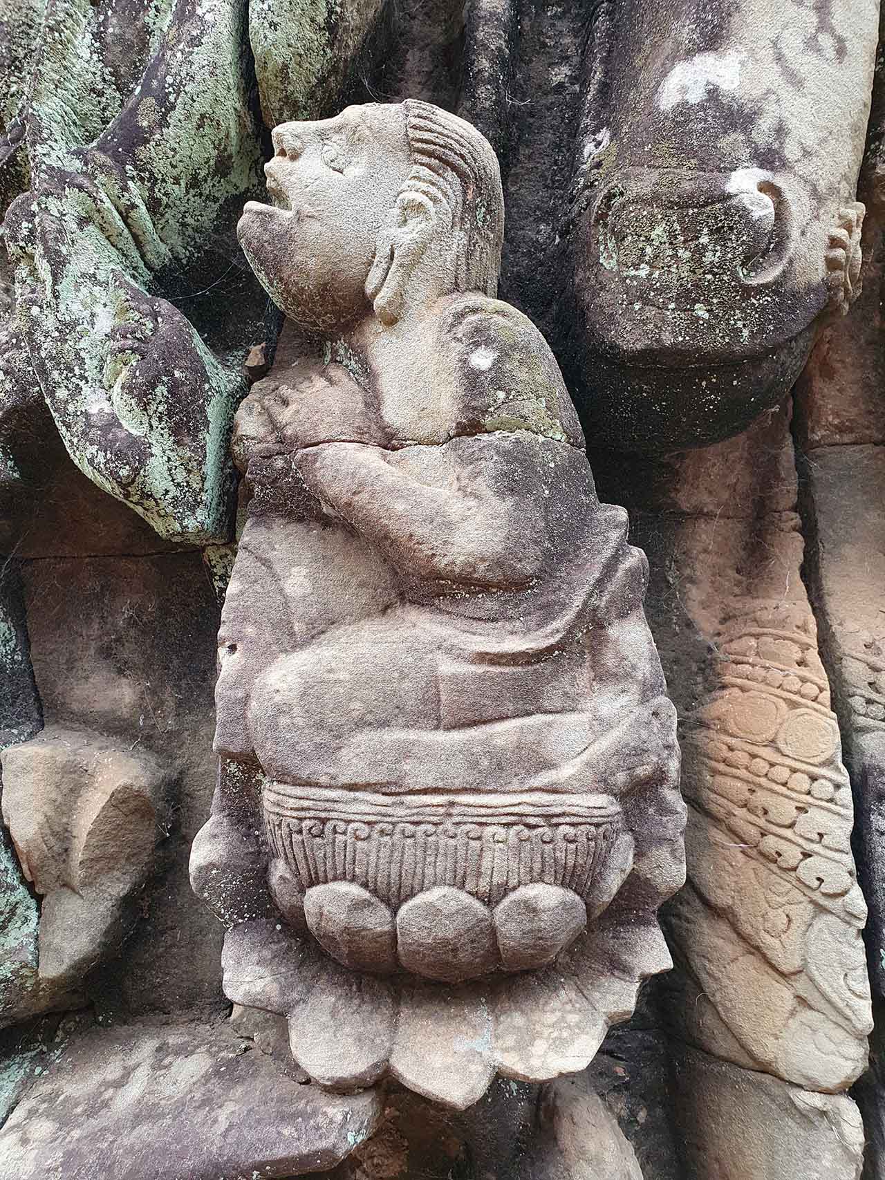 Chanteur dont le visage évoque une trisomie 21. On remarquera l'oreille dont le bas du lobe a cédé après avoir porté de lourds pendants d'oreilles ; il pourrait s'agir d'un homme âgé. Partie basse. © Patrick Kersalé 2022-2024.