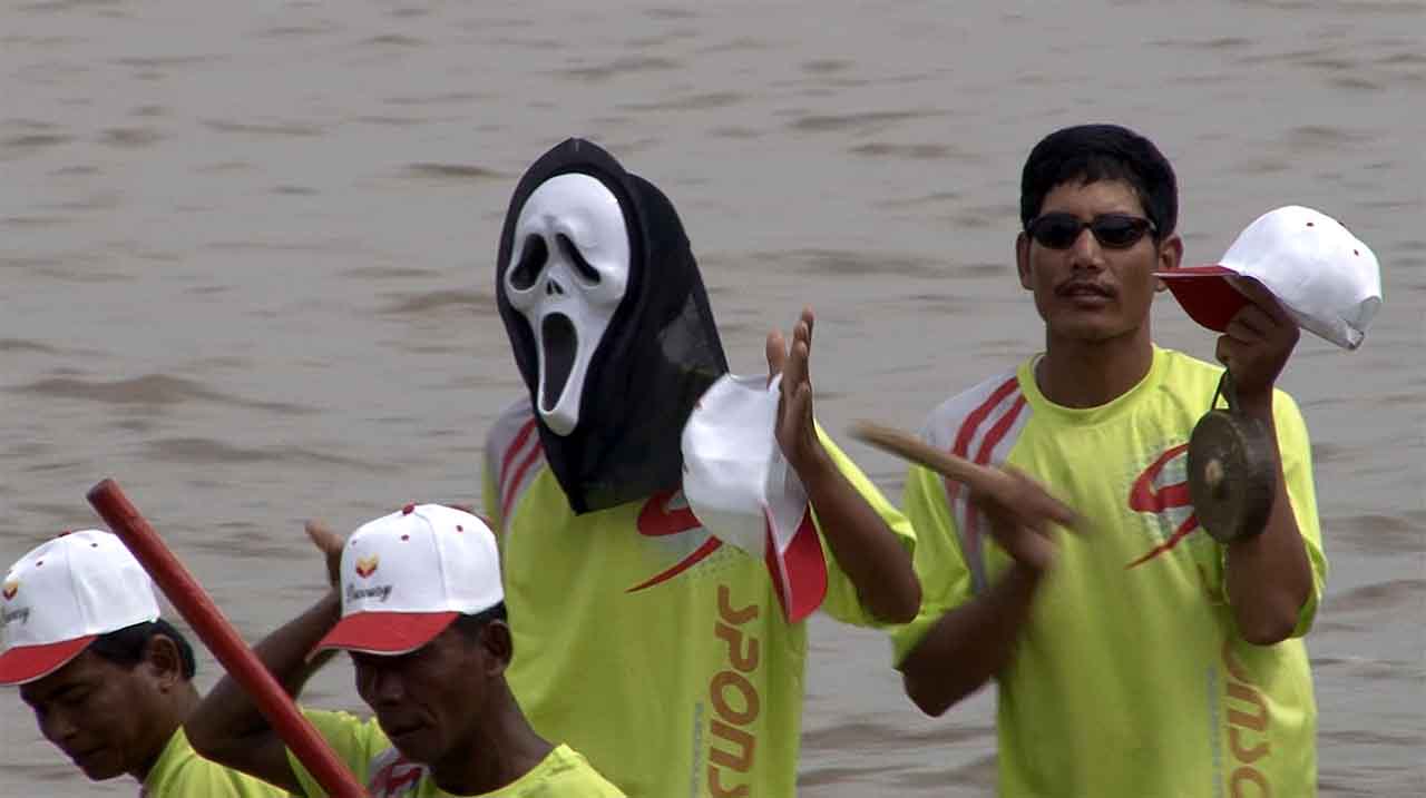   Bouffon engagé sur une pirogue de course durant la fête de l'eau en 2016 à Phnom Penh. © Patrick Kersalé 2016-2024.