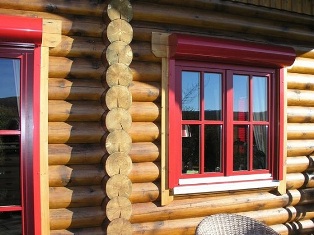 Holzbau - Komfortables Rundbohlenhaus mit roten Fensterrahmen 