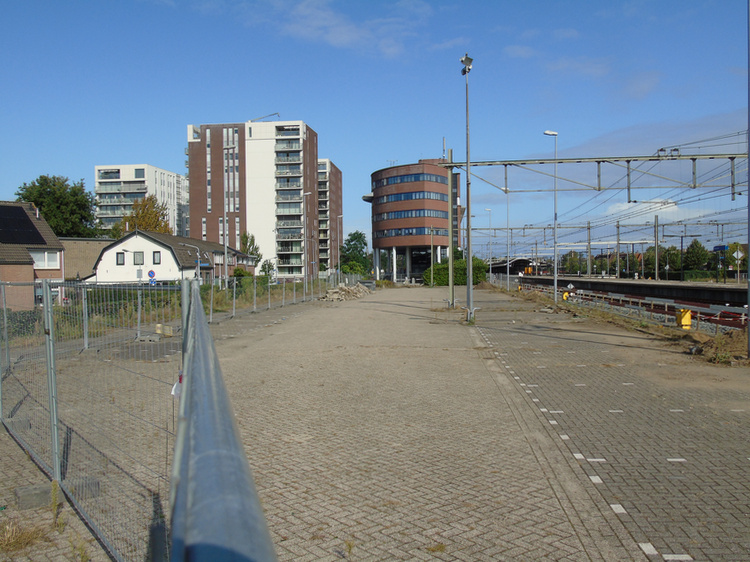 Tussen de flats en het kantoorgebouw loopt de busbaan het parkeerterrein op.