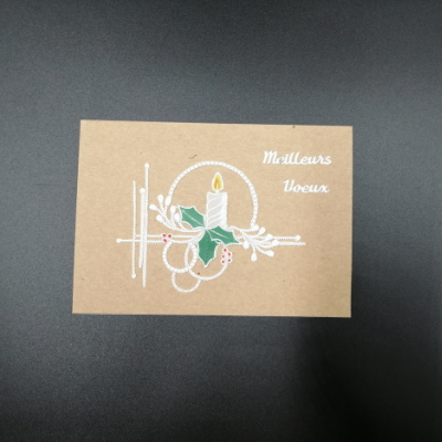 Bougie et branche de houx en dentelle de papier sur carte brune, marquée "Meilleurs Vœux"