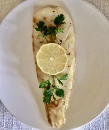 gegrilltes Fischfilet mit Zitrone und Petersilie dekoriert in einem Teller
