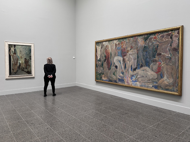 Person steht in einem Museum vor zwei Gemälden: Ein kleines Bild links und ein großes figuratives Gemälde mit mehreren Personen rechts.