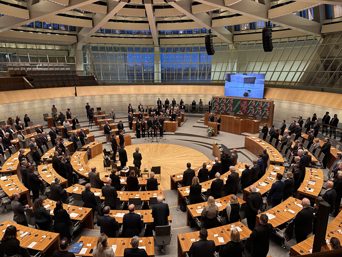 Blick in den Plenarsaal des NRW-Landtags. Abgeordnete stehen zum Gedenken an ihren Plätzen.