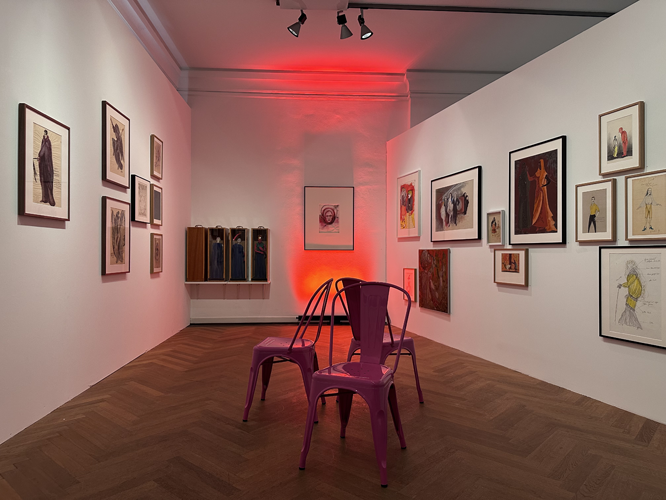 Ausstellungsraum mit Bildern, Stühlen und rotem Licht