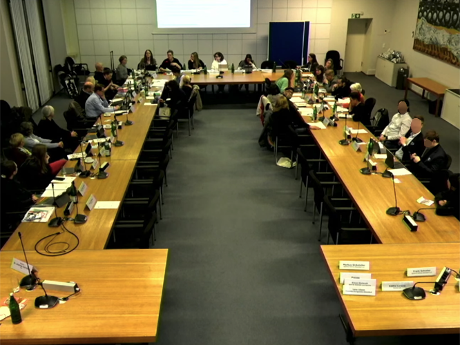 Blick in einen Sitzungssaal mit Personen an Tischen