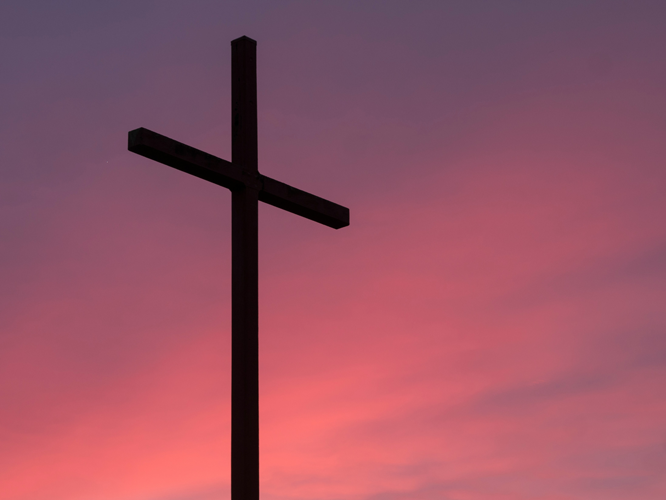 Kirchenkreuz vor rotem Himmel