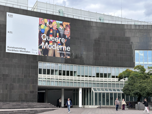 Eingang des Museums K20 in Düsseldorf mit einer großen Werbefassade für die Ausstellung 'Queere Moderne. 1900 bis 1950'