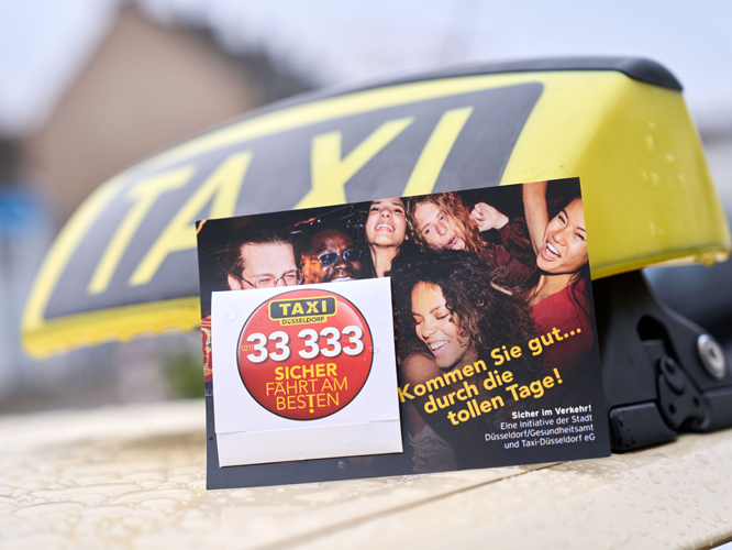Werbekarte auf einem Taxidach mit dem Slogan 'Sicher fährt am besten' und der Telefonnummer 33 333, umgeben von fröhlichen Menschen.