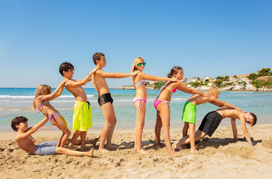 Eine Gruppe von Kindern spielt am Strand. Gut abgesichert mit einer günstigen Schüler-Reiserücktritts- und Reisekranken-Versicherung der Würzburger Versicherung/TravelSecure