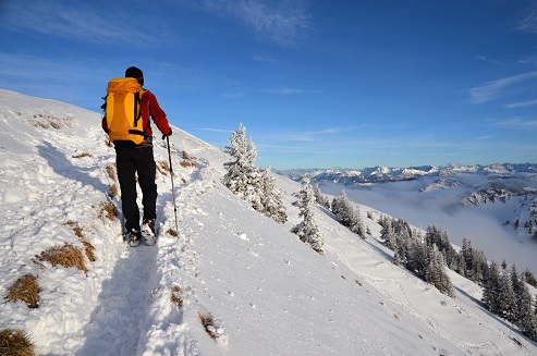 Mann beim Wandern im Winter in den Bergen mit Wander- und Bergsportversicherung