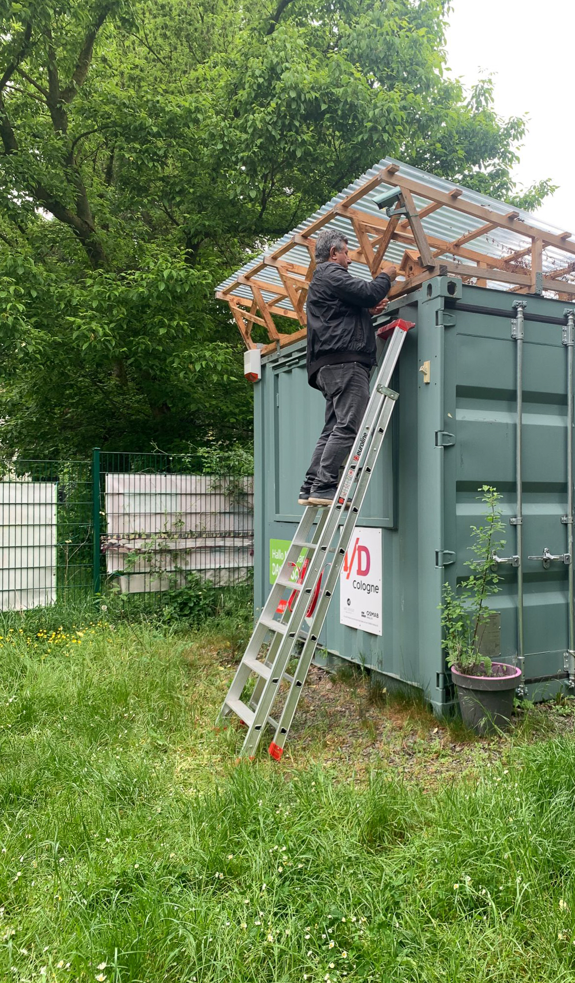 April 2026: Das Vogelhäuschen wird am Container angebracht