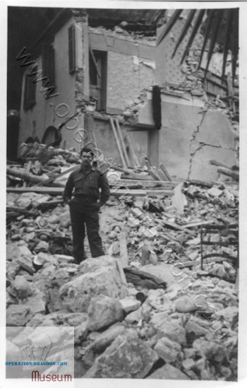Robert Cooper standing in the rubble of the inn that a time-bomb blew up, Nov. 4, 1944.