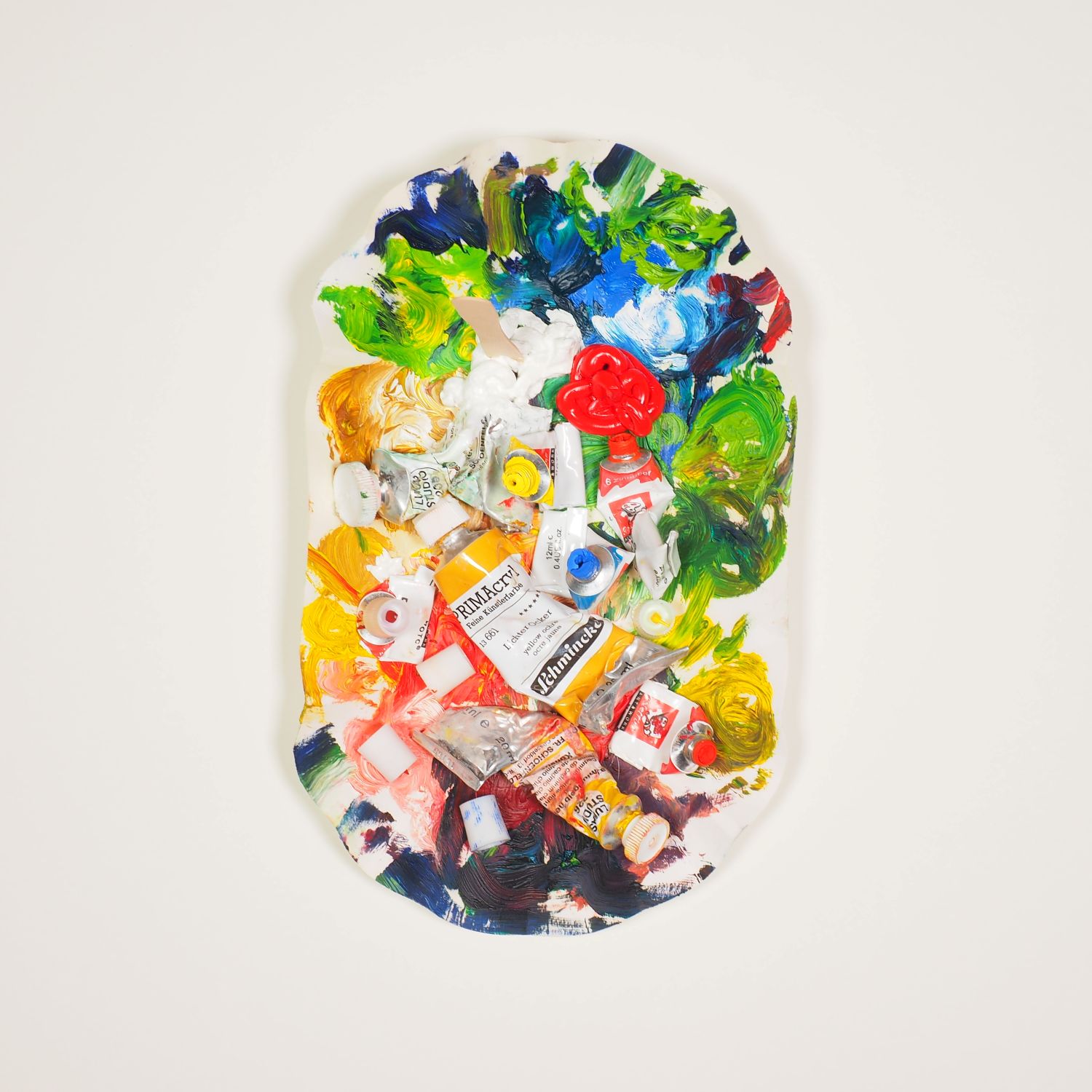 Assemblage aus alten Farbtuben, Ketchup und Majo auf einem mit Farbe beschmierten Pommesschälchen