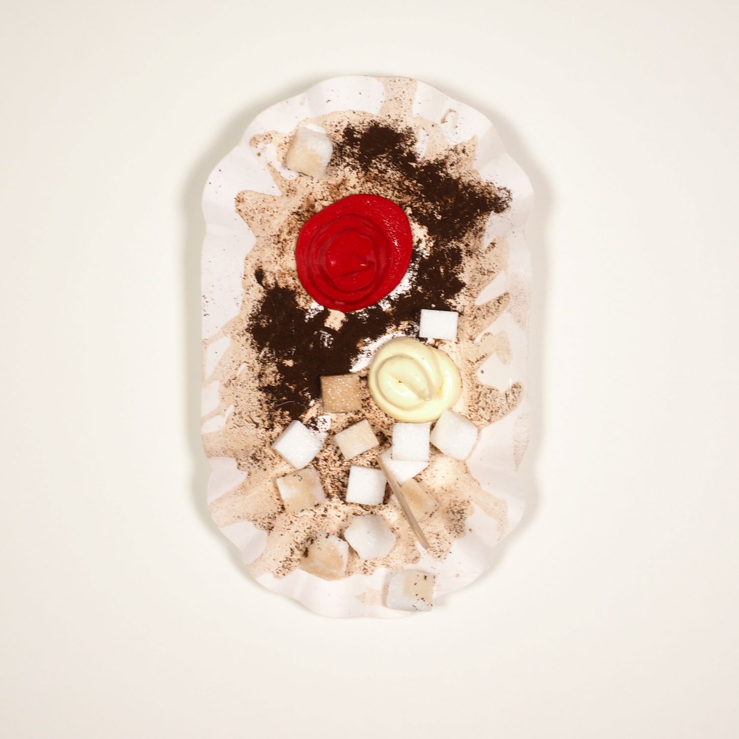 Assemblage von Kaffeeresten und Zuckerstücken auf einer Pommesschale