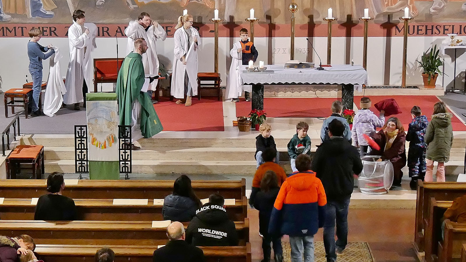 Erst vor dem Evangelium kommen die Ministranten und ziehen sich ihre Gewänder über.