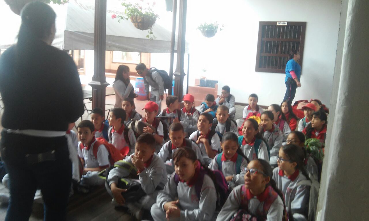 Niños y niñas del grado 4°A recibiendo la invitación para entrar al restaurante en compañía de la maestra en formación