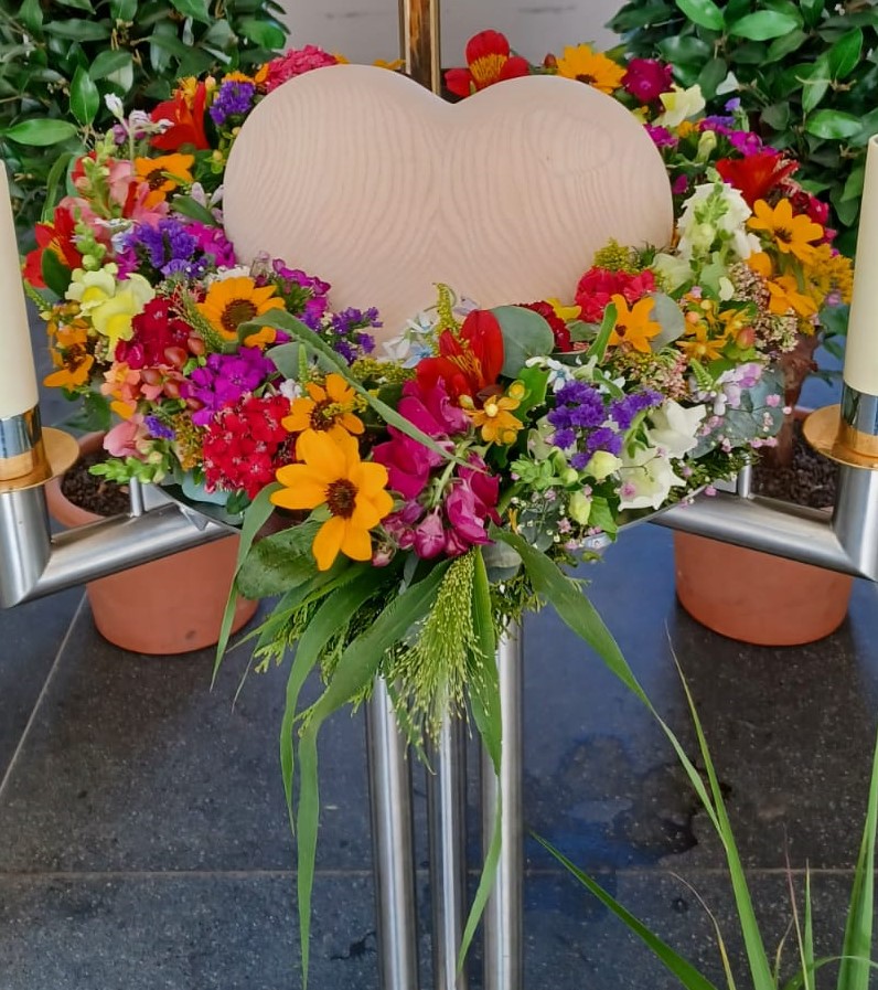 Ein Holzherz im Blumenbett in der Friedhofshalle Wiggensbach