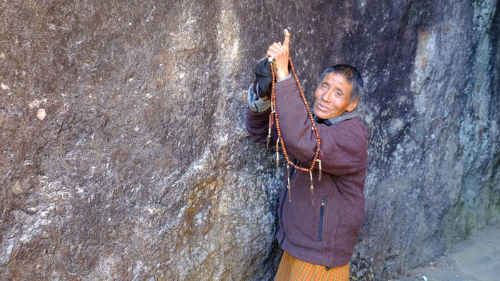 Ein lokaler Bhutanese erklärt uns die Fuss- und Handabdrücke, welche in der Felswand zu sehen sind