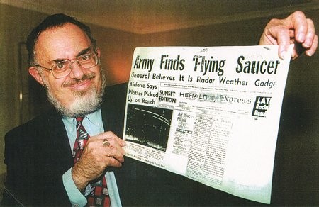 Stanton Friedman mostrando la portada del periódico “Los Angeles Herald Express” de 1947 en donde se puede apreciar un titular bastante interesante que indica el comienzo de una campaña de encubrimiento del tema OVNI por parte del gobierno de EE.UU.