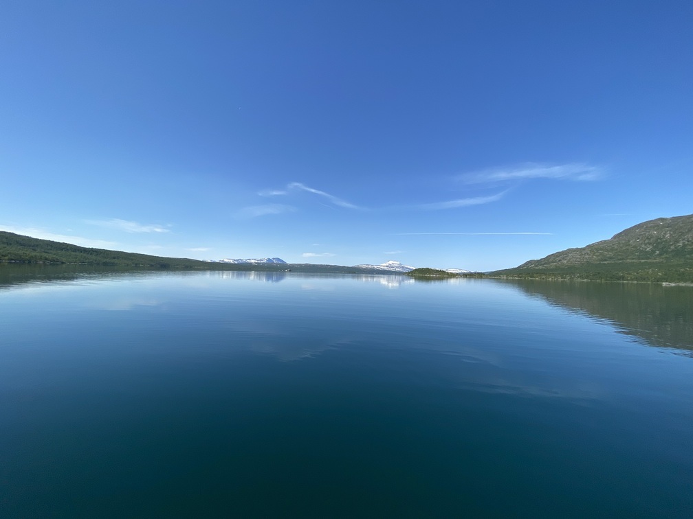 Panoramablick auf einen stillen, tiefblauen See bei blauem Himmel