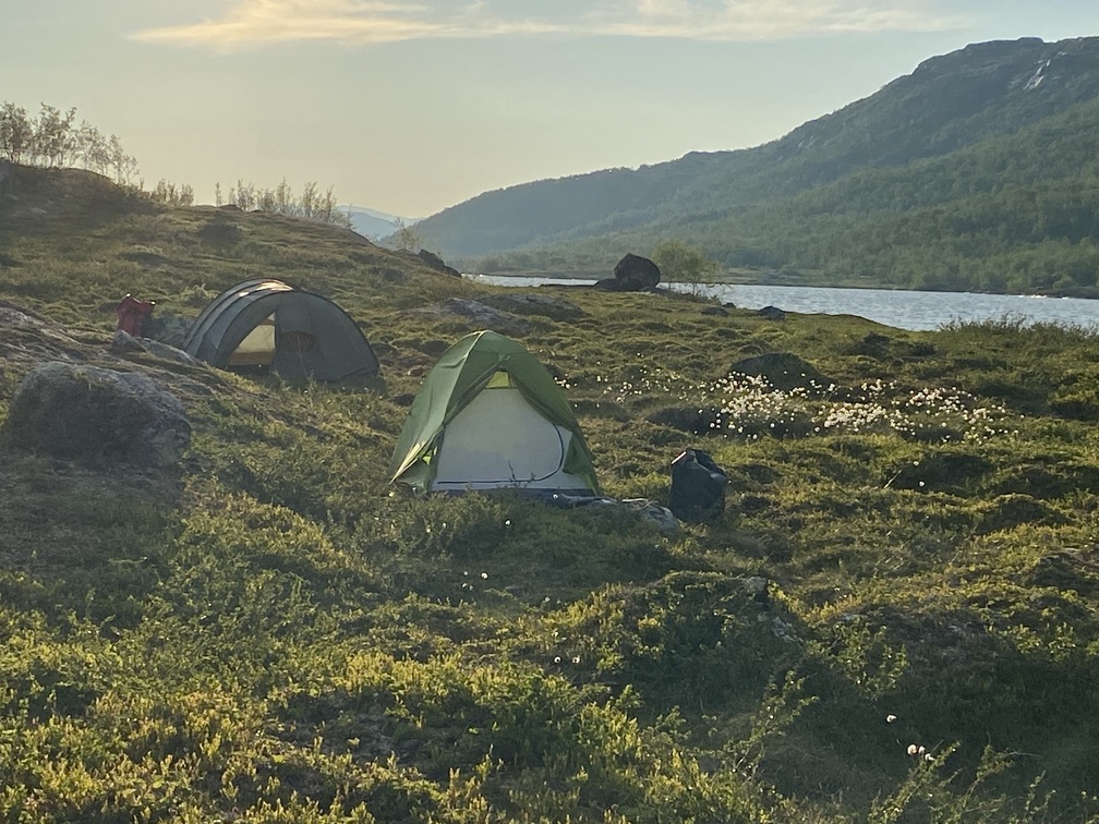 Kleines Zelt in einer hügeligen Landschaft am Seeufer