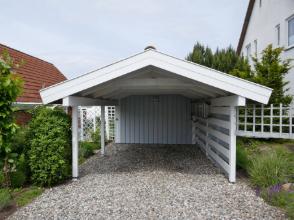 Klassischer Holzcarport mit Satteldach und seitlichem Sichtschutz, fachgerecht montiert auf Kiesfläche in Dresden.