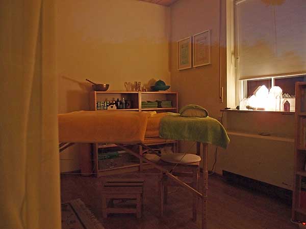 Behandlungsraum mit einer Liege, im Hintergrund am Fenster stehen die großen heilenden Bergkristalle von der Heiltherapeutin Dagmar Hiller.