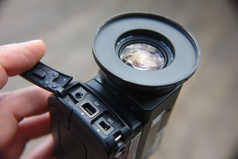 Die Fornt-Anschlüsse: Strom, AV-out, Kopfhörer (Achtung: Micro-Klinke!). USB liegt an der Seite. Statt Sonnenblende ein Übergangsring auf 58mm - damit ist jedweder Zubehör blitzschnell angeschraubt. habe ich 