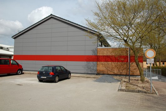 Der Eingang zur Turnhalle liegt rechts neben dem Gebäude und ist über einen Fußweg erreichbar.