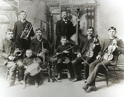 Zur Bach-Genealogie sieht man ein historisches Schwarz-weiß-Foto: Ein Vater und sieben Söhne sind die Bach-Band in den USA. Sechs sitzen, zwei stehen, Jeder hat ein Instrument.