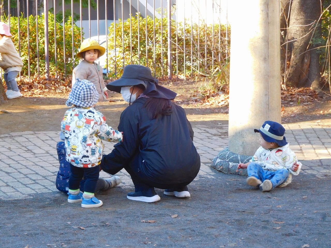 公園の端で遊ぶ幼児達と先生