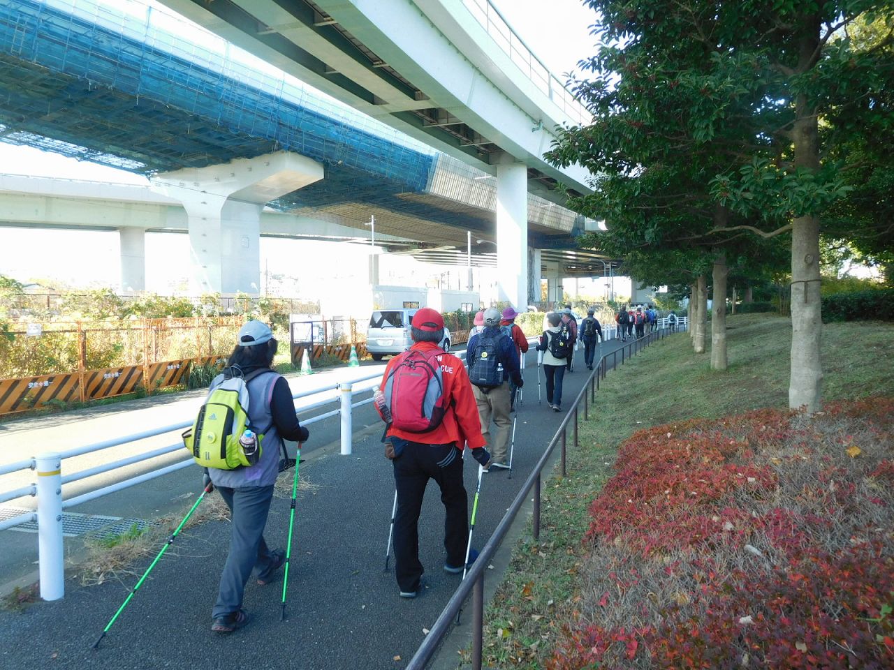 高速道路下を歩いてます　紅葉した木と赤いジャンバー