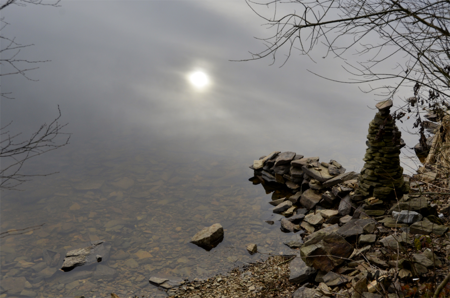 Steinstapel mit spiegelnde Sonne im Wasser