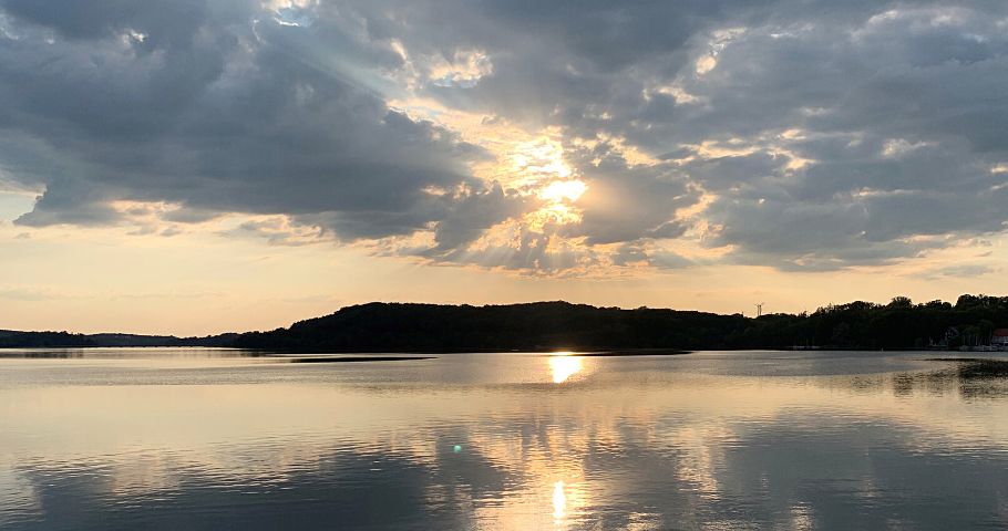 Die Abendsonne spiegelt sich im Wasser eines Sees