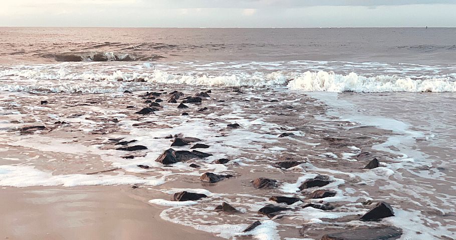 Steine im Sand in der Gischt des Meeres