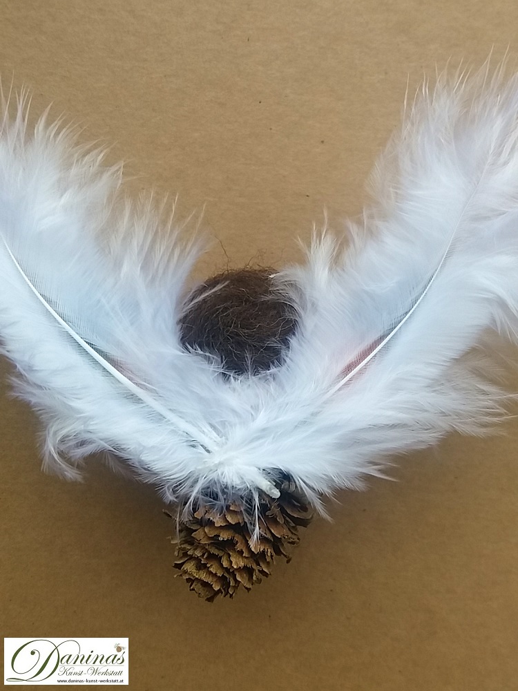 Schutzengel Figur Peachy Rückseite, handgefertige Engelfigur aus Lärchenzapfen mit braunen Haaren und buntem Haarband aus Wolle sowie bunten und weißen Federnflügeln.