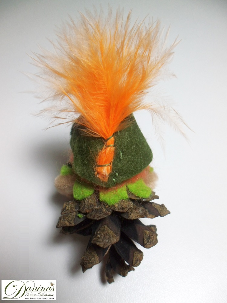 Peter Pan, Rückseite. Handgefertigte Dekofigur aus Kiefernzapfen mit einem Jäckchen und Hut aus grünem Filz mit einer orangen Feder.