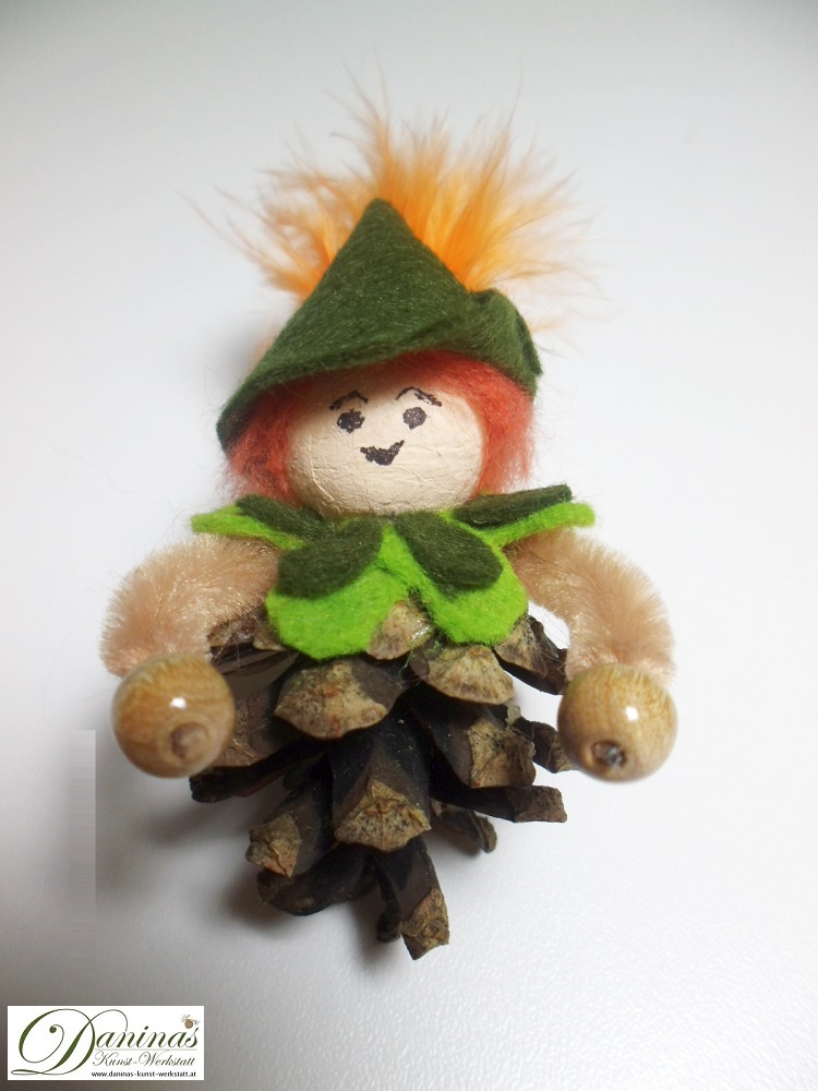 Peter Pan. Handgefertigte Märchenfigur aus Kiefernzapfen mit einem Jäckchen und Hut aus grünem Filz mit einer orangen Feder.
