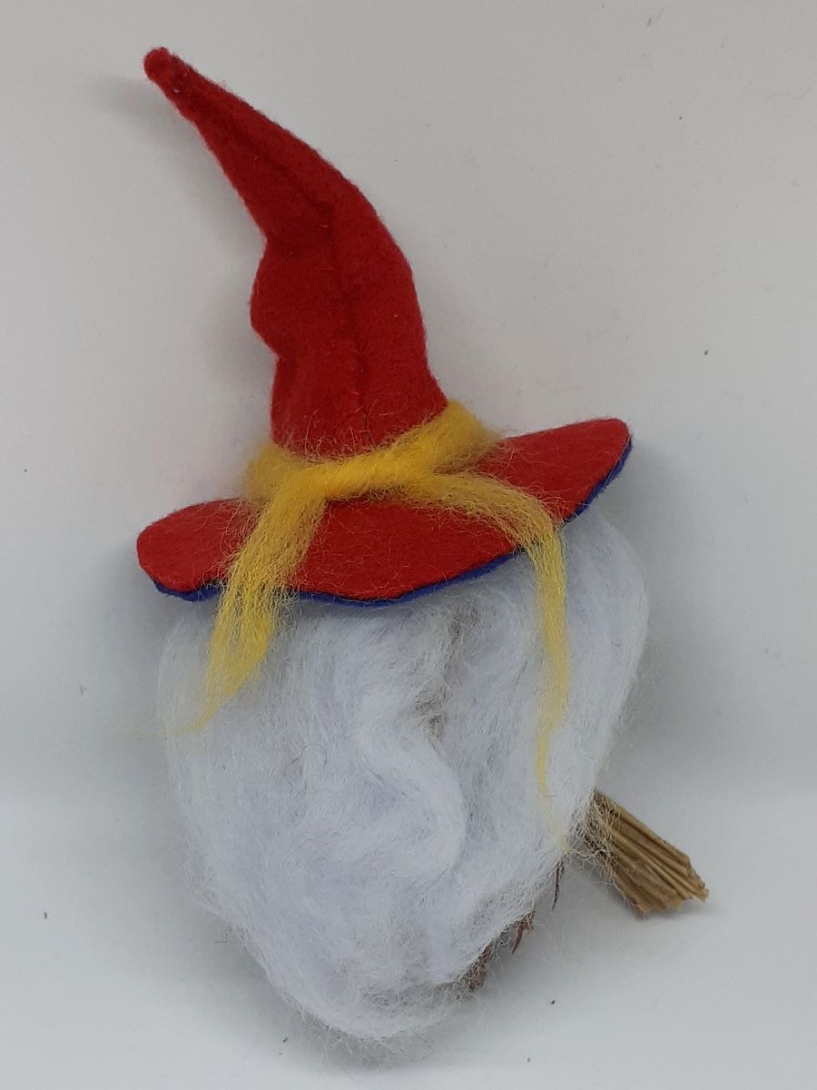 Hexe Aurora Rückseite. Handgefertigte Hexenfigur aus Douglasienzapfen, mit zartblauen langen Haaren aus Wolle, rot-blauen Hexenhut aus Filz, gelben Jäckchen, Hexenbesen aus Zweigen