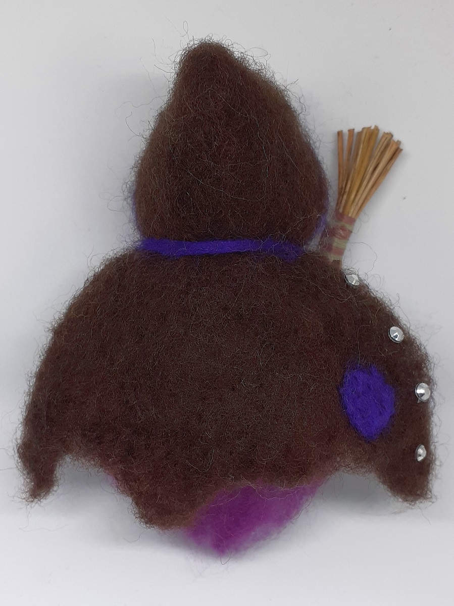 Hexe Viola Rückseite. Handgefertigte Figur aus Kiefernzapfen, mit violetten langen Haaren und nadelgefilztem braunen Hexenmantel aus Wolle, silberne Ziersteinen, Hexenbesen aus Kiefernnadeln