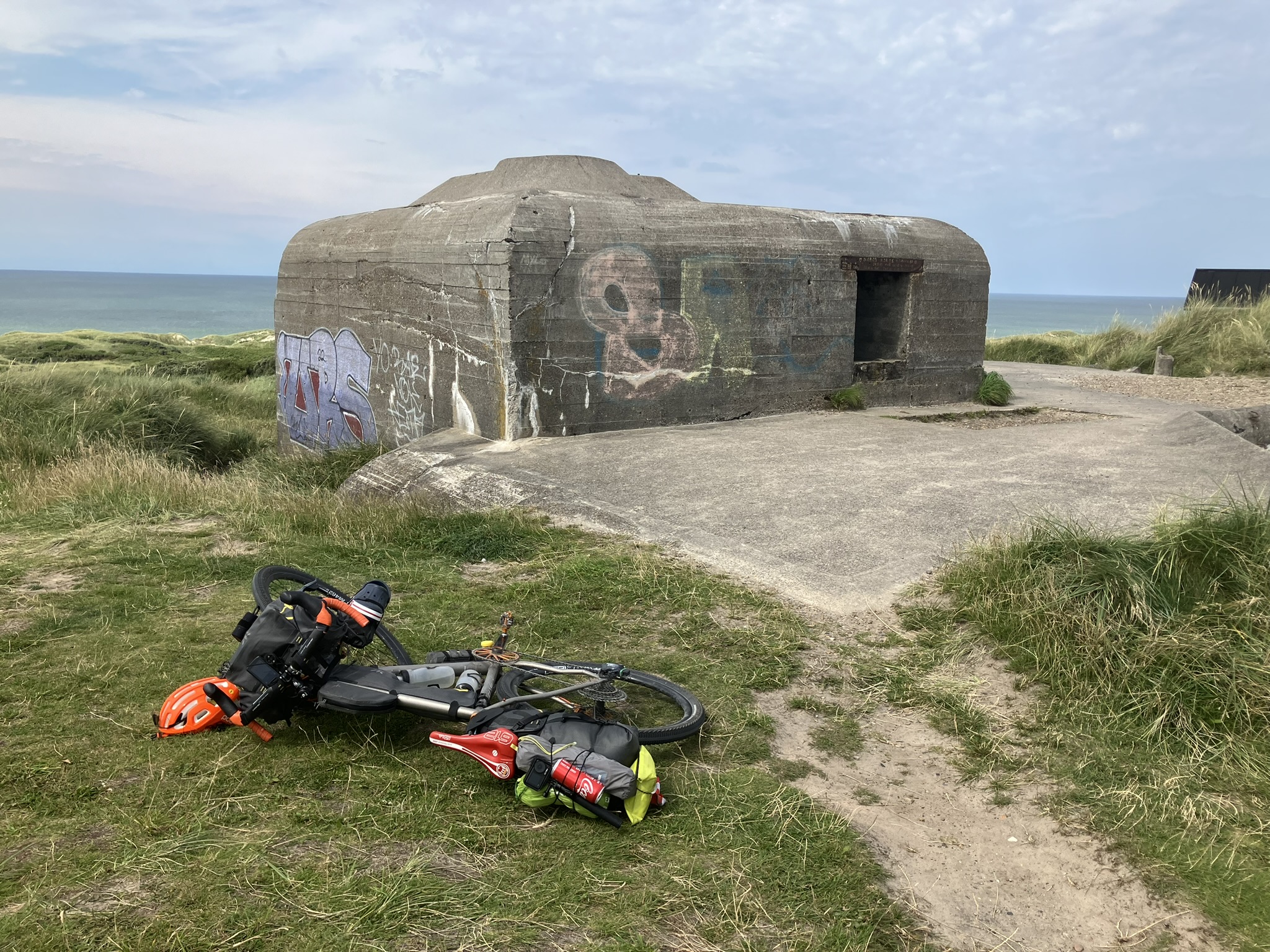 Bikepacking Dänemark - Gravelbike mit Gepäck vor historischem Bunker an der Nordseeküste bei Kettrup in Dänemark – Bikepacking entlang der Westküste.