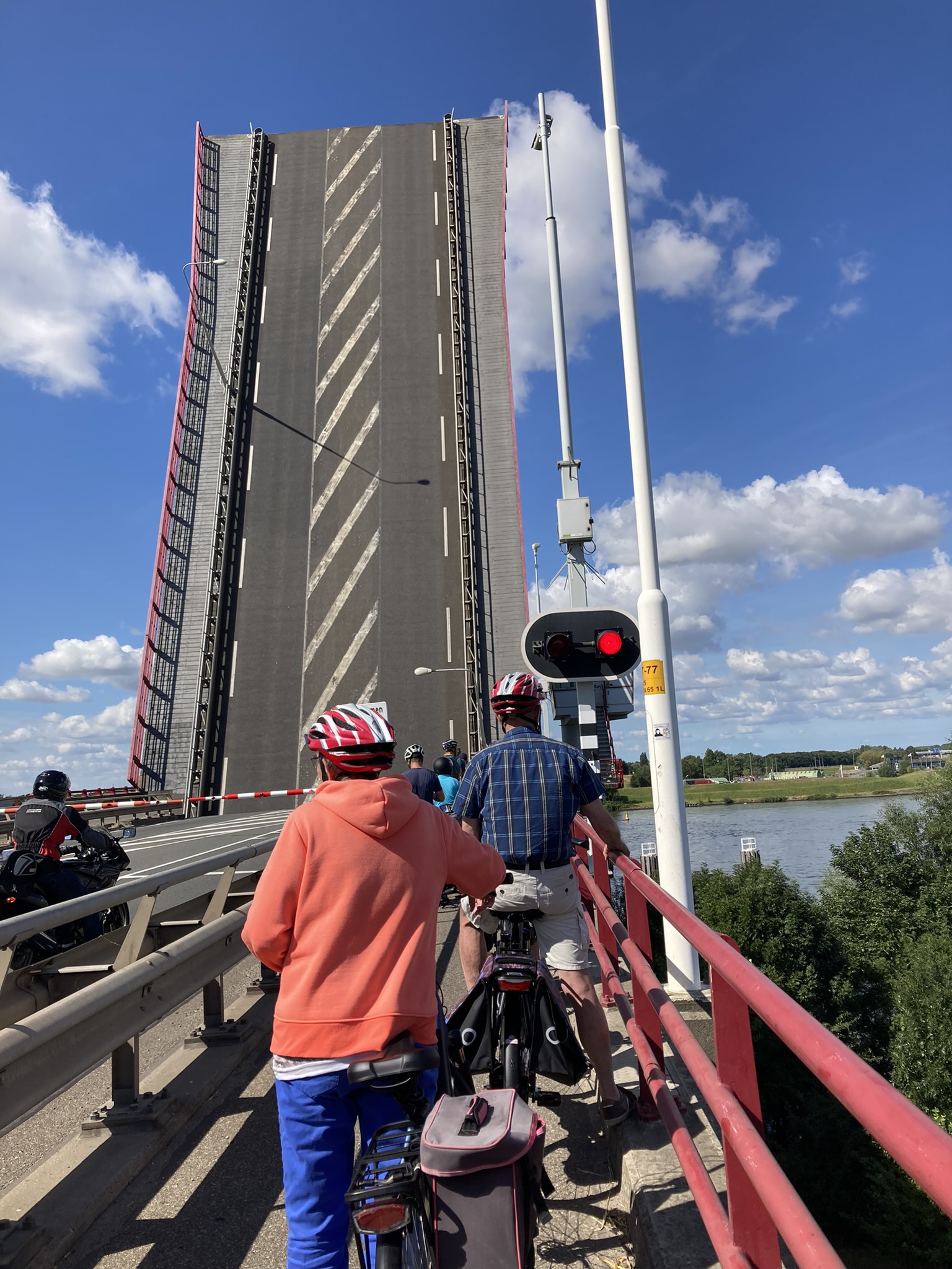 Bikepacking Niederlande – Radfahrer warten an geöffneter Klappbrücke auf der Route Groningen Amsterdam, flache Radwege entlang von Kanälen und Wasserstraßen in Holland.