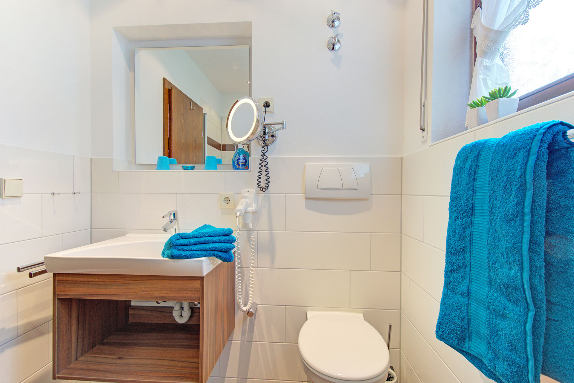 kleines badezimmer mit holzwaschtisch und türkisen handtüchern in apartment