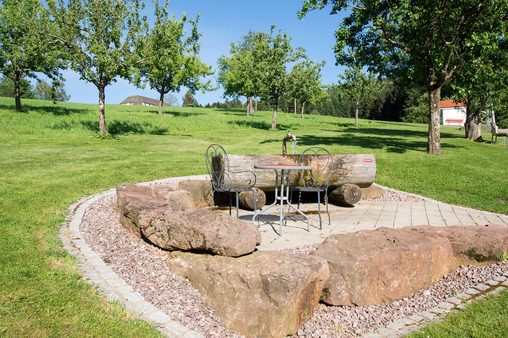 brunnen aus stein mit stitzgelegenheit mit und obstbäume beim ferienhof