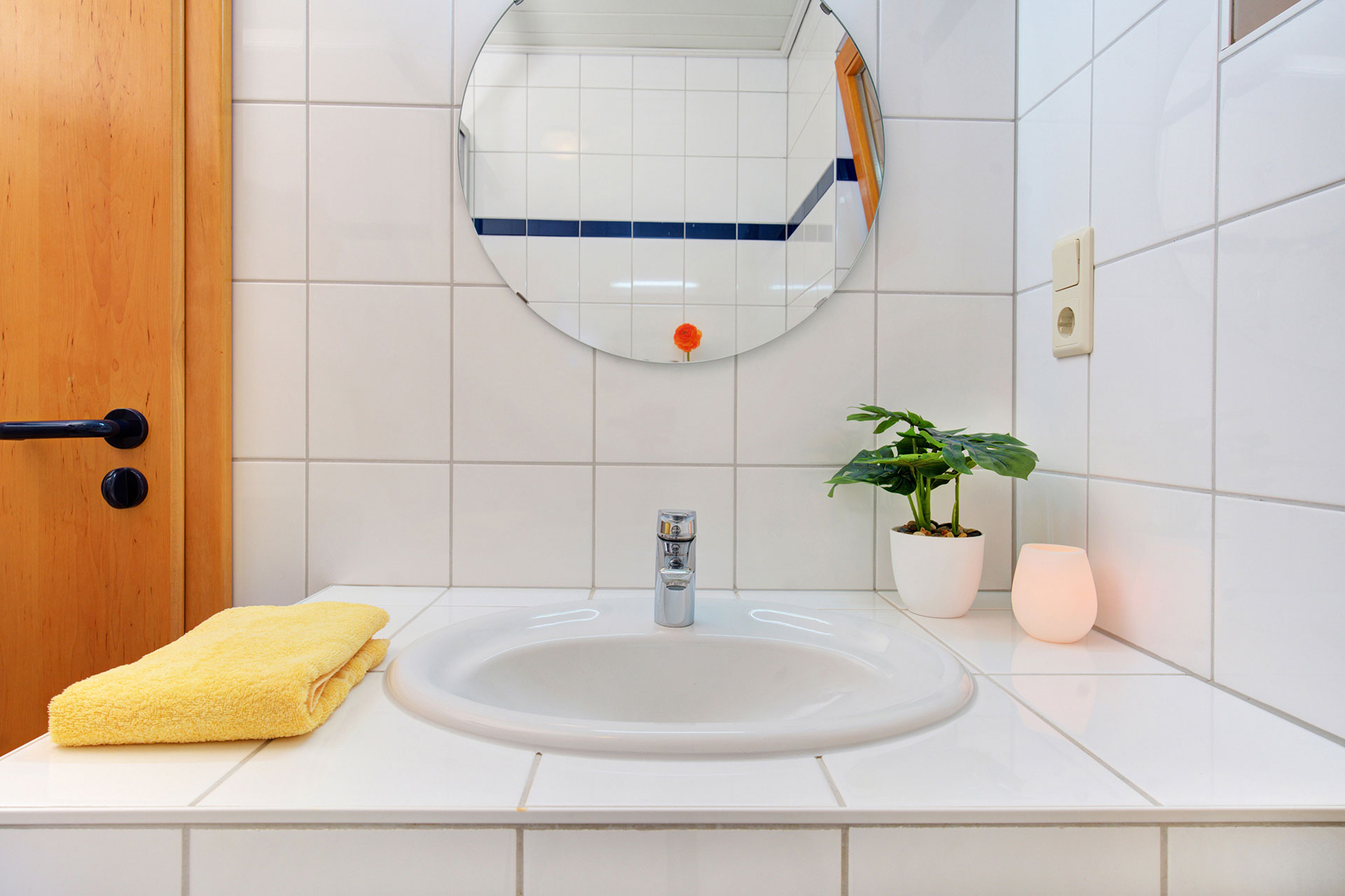 Badezimmer mit orangener led leuchte, gelbem handtuch und grünpflanze