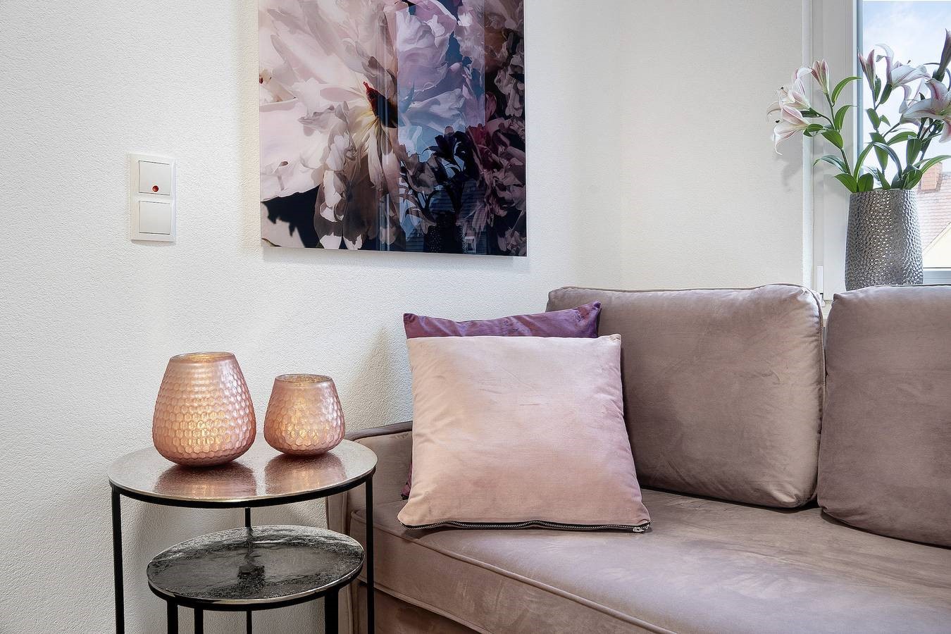 rosa teelichter auf kleinem tisch in ferienwohnung mit sofa kissen und blütenbild