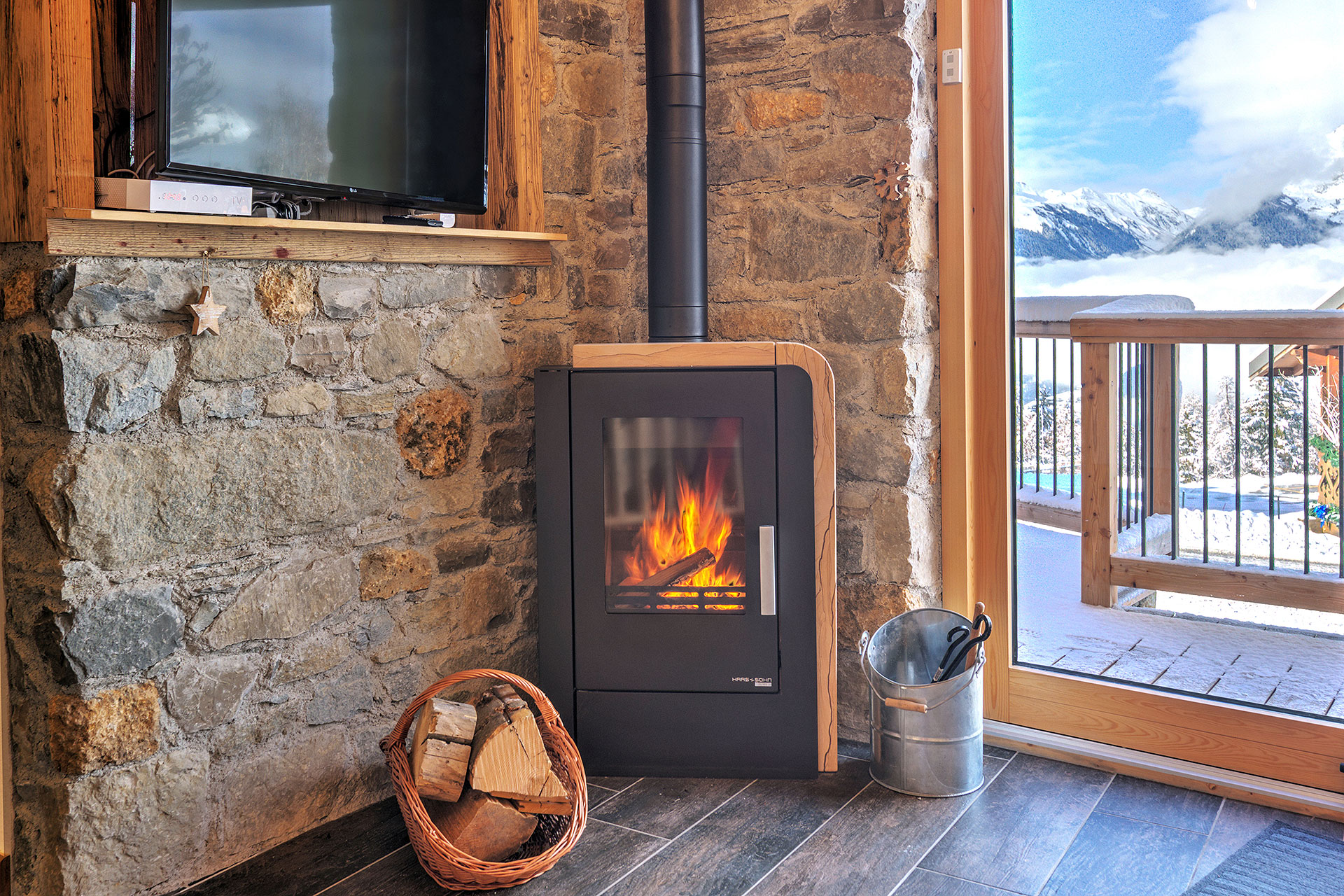 ferienhaus foto brennender kamin mit holzscheiten neben schneebergpanoramafenster